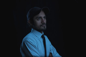 portrait with black background of a young man in cap shirt and tie