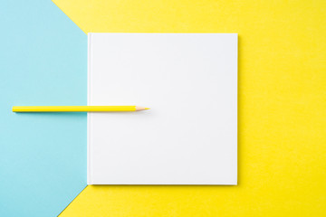 white square notebook on yellow and blue paper