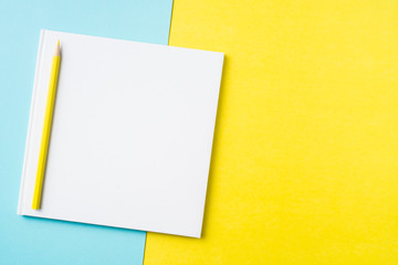 white square notebook on yellow and blue paper