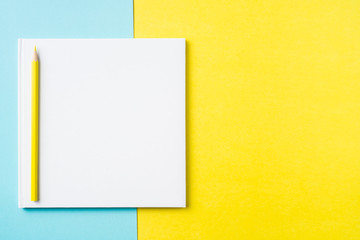 white square notebook on yellow and blue paper