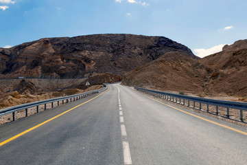 Driving on an empty road to the mountains through the desert, road to  good future