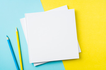 two white square notebook on yellow and blue paper