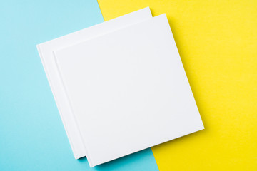 two white square notebook on yellow and blue paper