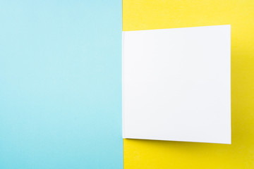 opened white square notebook on yellow and blue