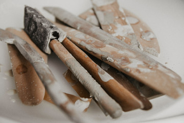 Set of dirty art and craft sculpting tools on wooden table in pottery workshop