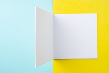 opened white square notebook on yellow and blue