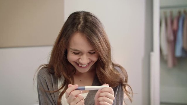Shocked woman positive pregnancy test result. Portrait of pregnant woman test