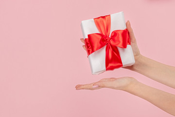 Woman presenting gift box with red bow 