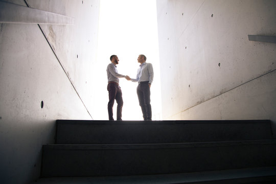 Two businessmen shaking hands in a passageway