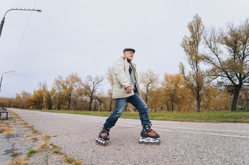 Fototapeta premium Active retiree rollerblading and making extreme turns. Autumn walks in the fresh air.