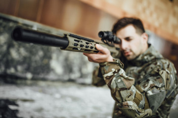 A military soldier targets and holds a large rifle in the building