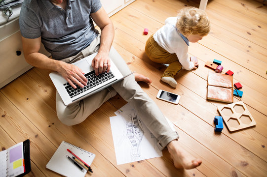 Father at home with his little son using laptop