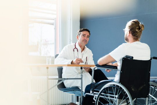 Doctor listening to patient in wheelchair in medical practice