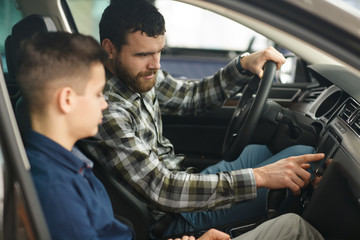 Handsome mature man and his young son buying a new automobile together