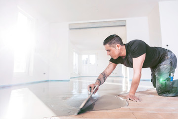 Bodenleger arbeitet mit selbstnivellierendem Zementmörtel. 