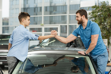 Handsome mature man and his young son buying a new automobile together