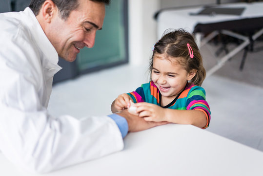 Doctor with plaster and happy girl at desk in medical practice