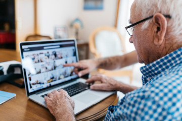 Adult grandson teaching his grandfather to use laptop