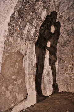 Sombra de pareja bes&aacute;ndose en muro de piedra