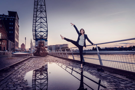 Barfoot businesswoman dancing at wet inner harbor