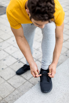 Young man during workout, tying shoes