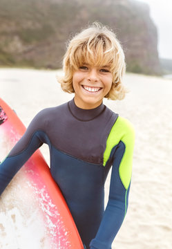 Spain, Aviles, portrait of smiling young surfer on the beach