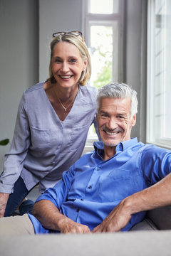 Portrait of smiling mature couple on couch at home