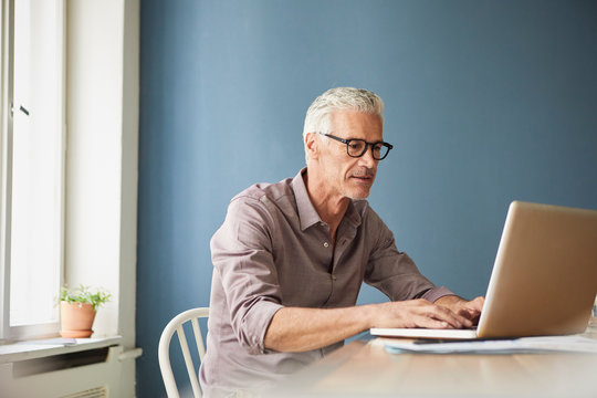 Mature man using laptop on table at home