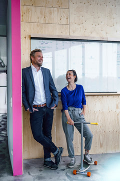 Mature man and his assistant with scooter, standing in office in front of white board