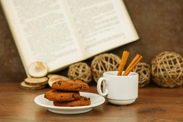 Chocolate cookies in a plate and a cup on a wooden table