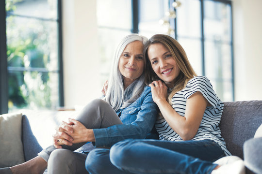 Daughter holding mother in her arms, sitting on couch