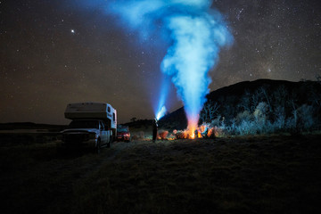 Chile, Tierra del Fuego, Lago Blanco, campfire and people at camper under starry sky at night