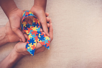 Hands holding puzzle ribbon, World Autism Awareness Day, Autism spectrum  disorder - obrazy, fototapety, plakaty