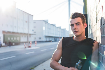 Germany, Mannheim, Young athlete in the city with bottle of water, portrait