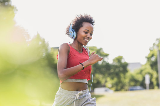 Young woman with headphones running in park