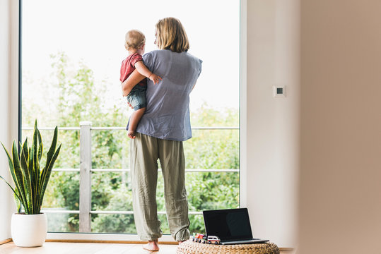 Mother carrying son, looking out of window