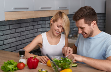 Couple preparing salad in stylish kitchen
