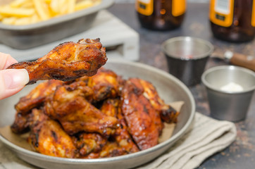 Hot and spicey Buffalo chicken wings. Fried chicken wings. Baked chicken wings in the Asian style. Holding a chicken wing