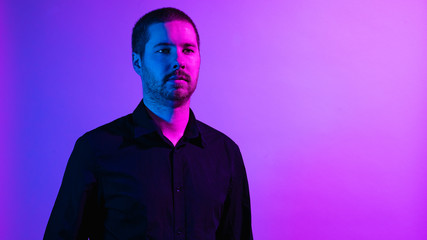 Serious unshaven man in vivid purple lighting