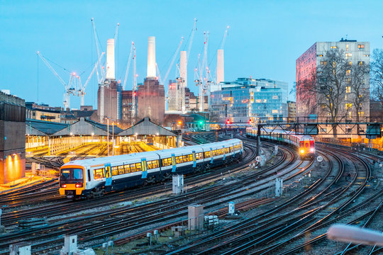 United Kingdom, England, London, view of rail tracks and trains in the evening, former Battersea Power Station and cranes in the background