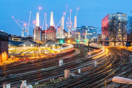 United Kingdom, England, London, view of rail tracks and trains in the evening, former Battersea Power Station and cranes in the background