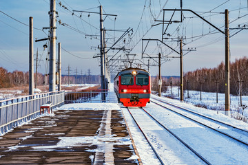 Local passenger train approaches to the station at winter morning time.