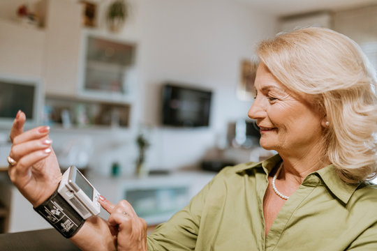 Smiling senior woman taking her blood pressure