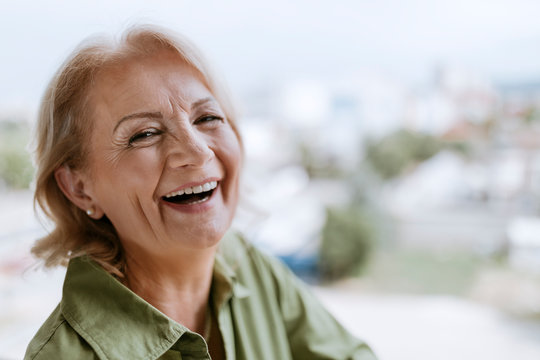Portrait of laughing senior woman with hearing aid outdoors