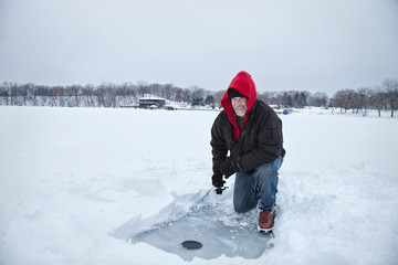 Fototapeta na wymiar A smiling middle aged man ice fishing on a lake in Minnesota during winter