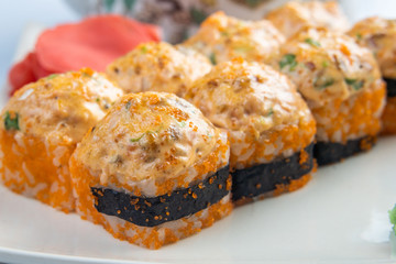 Baked rolls with scallop , spicy sauce, cream cheese and mango with rice on white plate with gold border. Asian menu