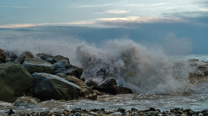 Sea surf on rocks at coastline. Stormy weather. Gloomy sky. Bad weather.