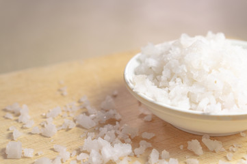 Salt in a white cup on a wooden floor.