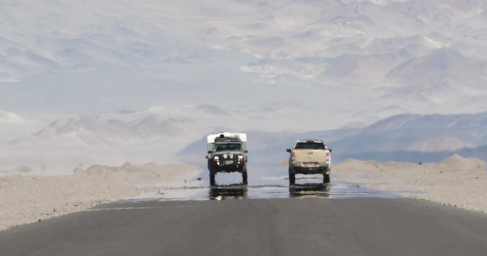 Still scene of 4x4 van with caravan traveling over road with heat haze effect at desert and mountainous dry region. Water vapor ilusion. Mirage. Antofagasta de la Sierra,Catamarca, Argentina