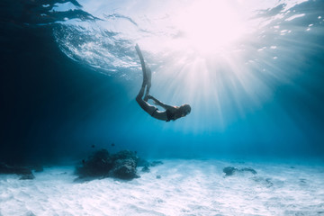 Woman freediver dive over sandy sea with fins. Freediving in blue ocean